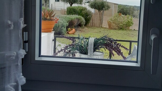 A window with a view of a garden and a building. - Monte da Rua 13 - Casa de Aldeia (Redondo)