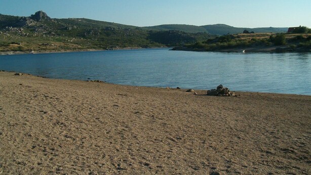 Una spiaggia con un litorale roccioso e un lago tranquillo.