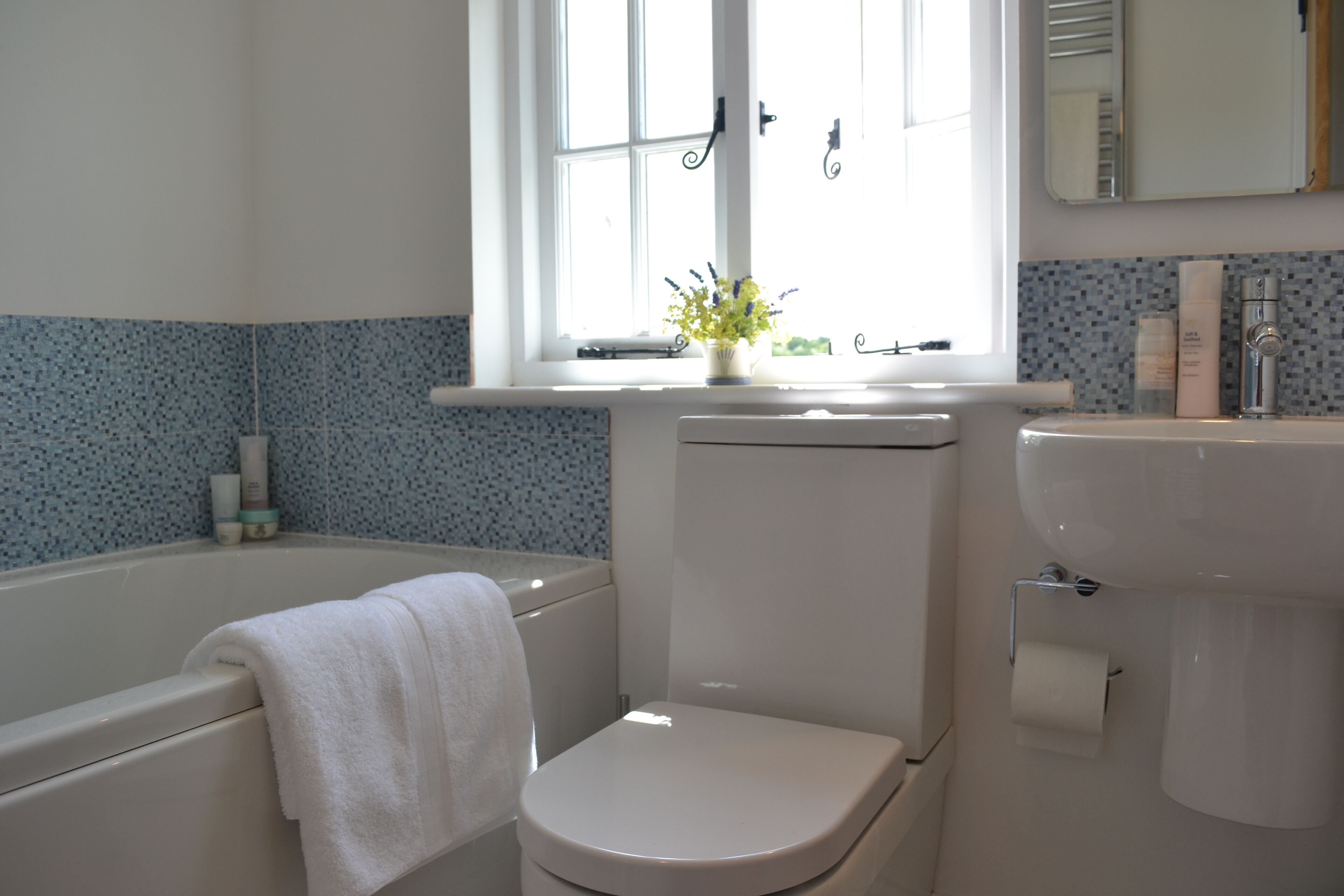 A bathroom with a bathtub, toilet, sink, and a window with a view.