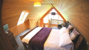 Ein gemütliches Schlafzimmer im Dachgeschoss mit Bett, Schreibtisch und Fenster.