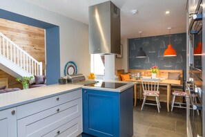 Une cuisine moderne dotée d’un îlot central, d’un coin repas avec une table et des chaises en bois, et d’un escalier menant à un autre niveau.