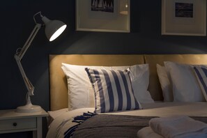 A neatly made bed with striped pillows, a bedside lamp, and a framed picture on the wall.
