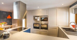 A modern kitchen with stainless steel appliances, a built-in oven, and a sink.
