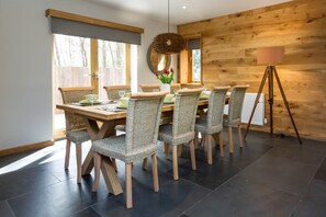 Un coin repas avec une table en bois et des chaises en osier, un miroir au mur et un lampadaire sur trépied.