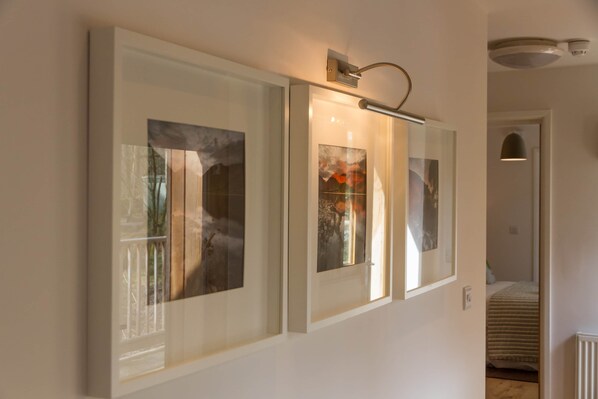A hallway with framed artwork on the wall, a ceiling-mounted light fixture, and a radiator.