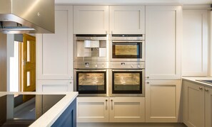 Une cuisine équipée d’un four encastré, d’un four à micro-ondes et d’une plaque de cuisson.