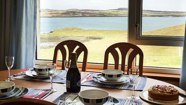A dining table set for four with a view of a lake and hills.