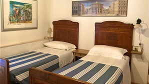 A hotel room with two single beds, wooden headboards, a nightstand with a lamp, and two framed artworks on the wall. - Casa Marola, house with character (Gabicce Mare)