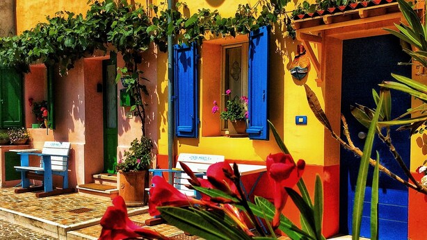 A colorful building with a blue door, a sign reading "CASA MAROLA", and a small table outside. - Casa Marola, house with character (Gabicce Mare)