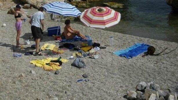 A rocky beach with people sunbathing and a striped umbrella. - Ranch Studio in Quiet White Village Setting with shared Pool and Hot Tub (Castell de Ferro)