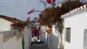 A narrow alleyway with white buildings, a small tree, and red flowers. - Ranch Studio in Quiet White Village Setting with shared Pool and Hot Tub (Castell de Ferro)