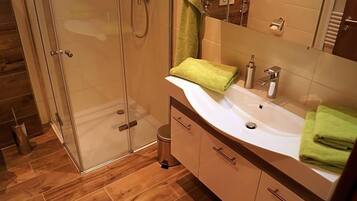 Een moderne badkamer met een douchecabine van glas, een wit wastafelmeubel en een houten vloer.