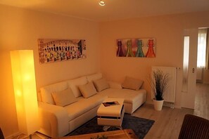 A living room with a sofa, a coffee table, a lamp, and wall art.