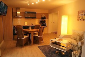 A modern kitchen with a dining area, a sofa, and a coffee table. - Landhotel Klempau (Krummesse)