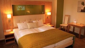 Een hotelkamer met een groot bed, twee nachtkastjes, een bureau en een stoel.
