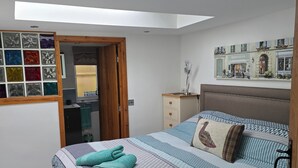 A bedroom with a bed, a nightstand, a dresser, a window with a view of a street, and a skylight. - Coppice, Entire 1 bedroom annex, pet friendly. EV Charger.  (Barton on Sea)