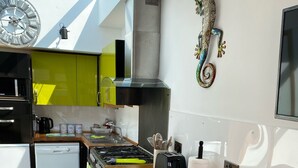 A modern kitchen with a wooden countertop, stainless steel appliances, and a decorative seahorse wall art piece. - Coppice, Entire 1 bedroom annex, pet friendly. EV Charger.  (Barton on Sea)