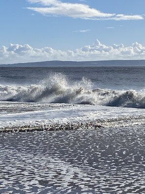 Una playa con olas rompiendo en la orilla y cielo despejado.
