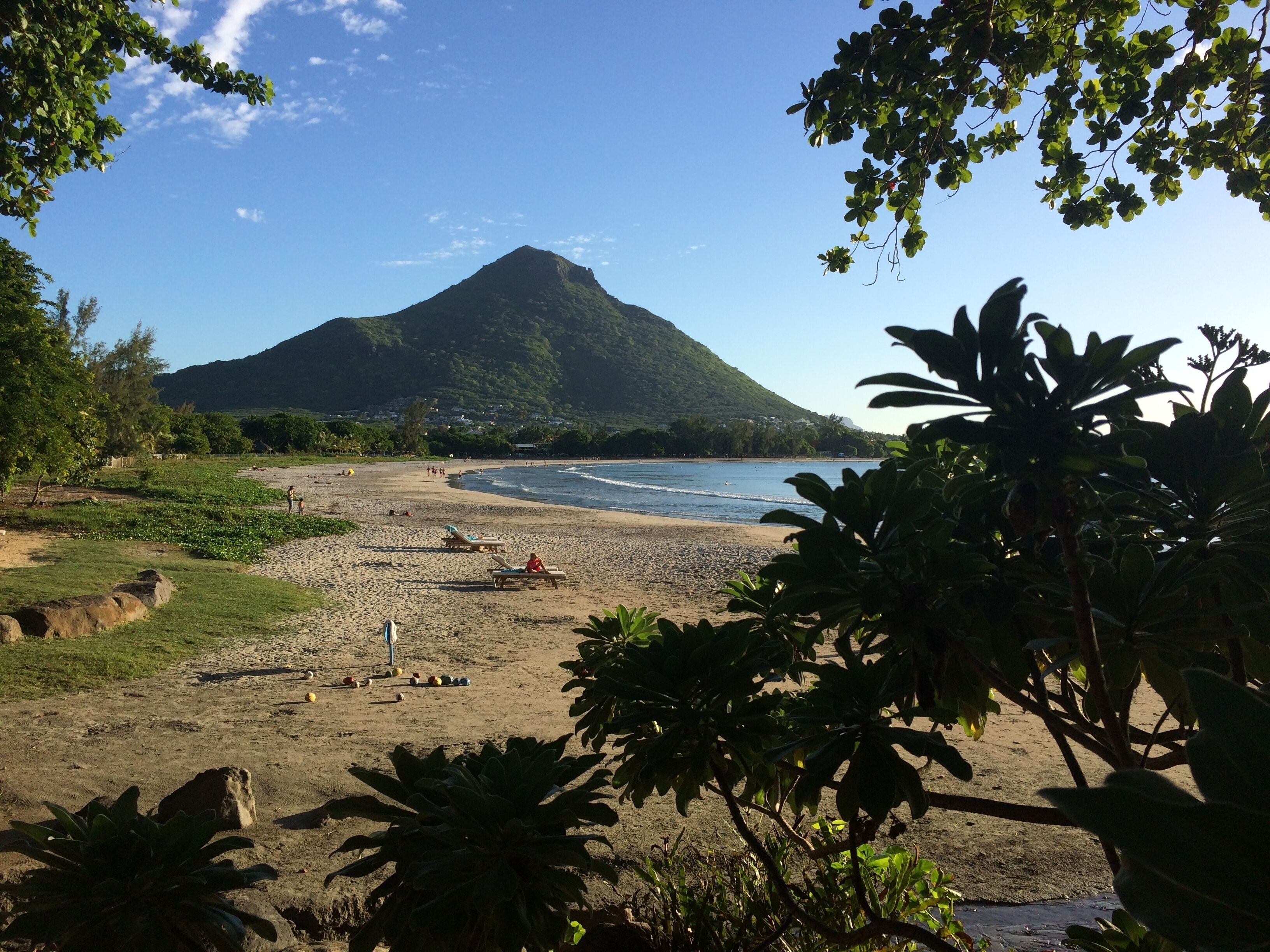 Une plage avec une montagne en arrière-plan, entourée de verdure.
