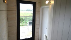 Une pièce avec une porte donnant sur un balcon, un radiateur et un luminaire fixé au mur.