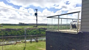 Un mur de briques avec une structure en verre donnant sur une zone herbeuse et une étendue d’eau.
