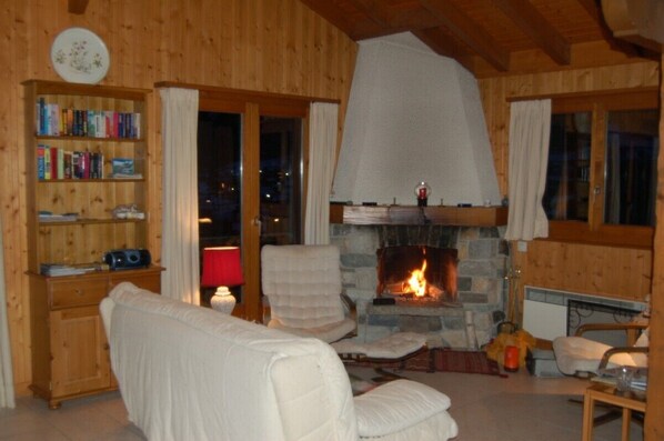 A cozy room with a fireplace, a bookshelf, and a comfortable seating area. - Near Verbier peaceful Swiss village, stunning views (Levron)