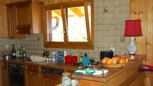 Eine Küche mit Holzausstattung, einem Herd, einer Spüle und einem Fenster mit Blick ins Freie.