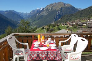 A dining table set on a balcony with a mountain view, surrounded by white chairs. - Near Verbier peaceful Swiss village, stunning views (Levron)