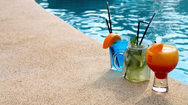 Una piscina con juguetes inflables y bebidas en el borde.