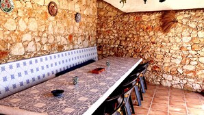 Un área de comedor al aire libre con paredes de piedra, una mesa y sillas estampadas.