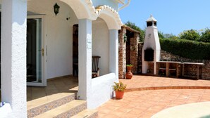 Un edificio con fachada blanca, una torre de piedra y un patio con una planta en maceta.