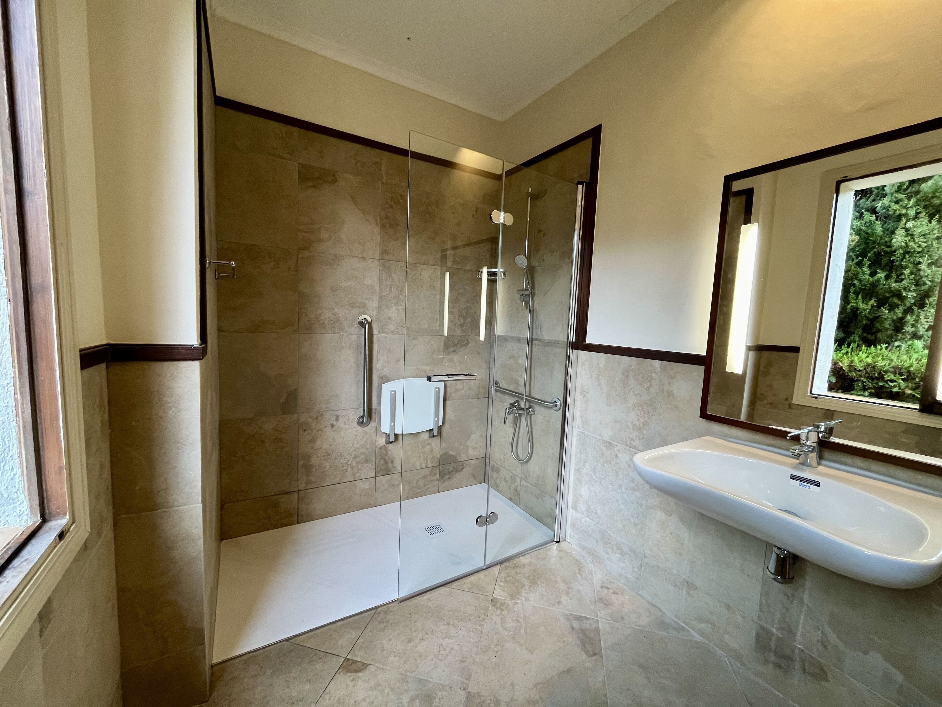 A modern bathroom with a glass-enclosed shower, a white sink, and a large mirror.