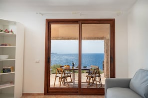 Enjoy breathtaking sea views from this room, featuring a sliding glass door to an outdoor area with a table and chairs.