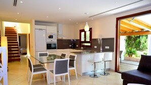 Una cucina moderna con zona pranzo, una scala e vista sul verde.