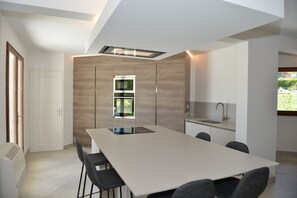 A modern kitchen with a large island, built-in appliances, and a window.
