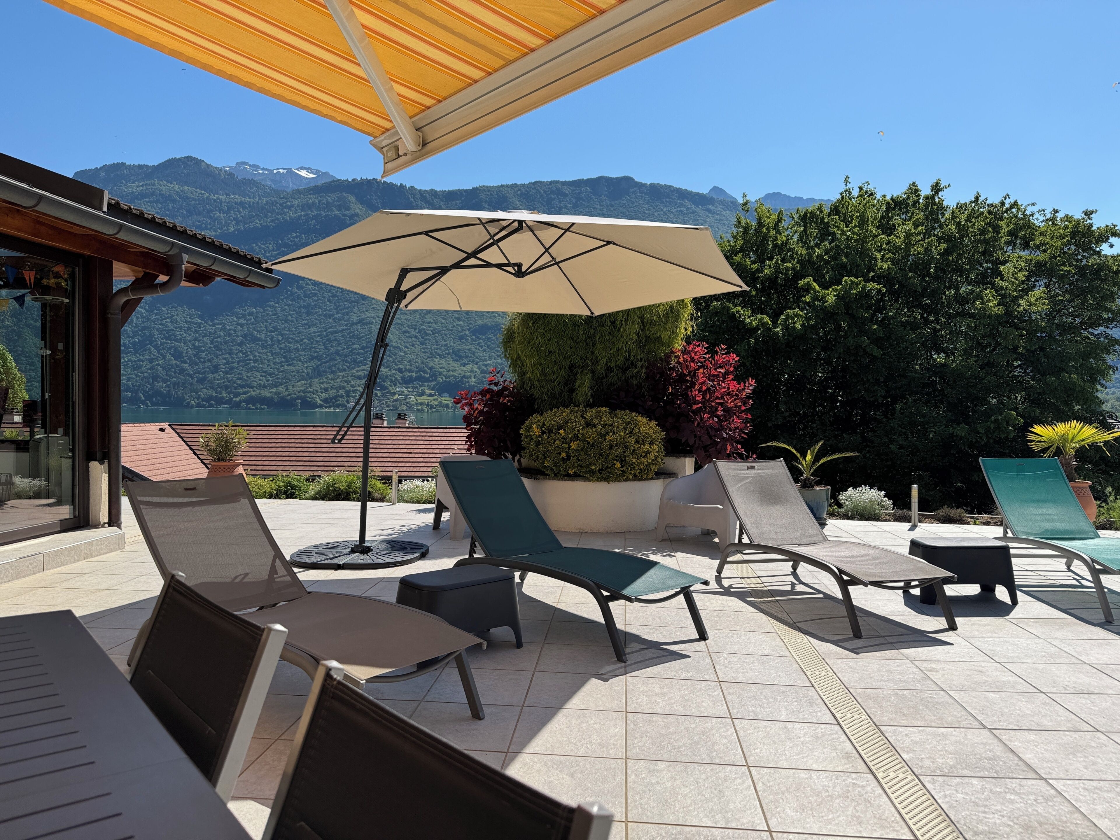 A terrace with lounge chairs, a table, and a large umbrella.