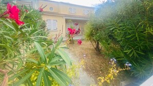 Un jardín con un edificio amarillo al fondo.