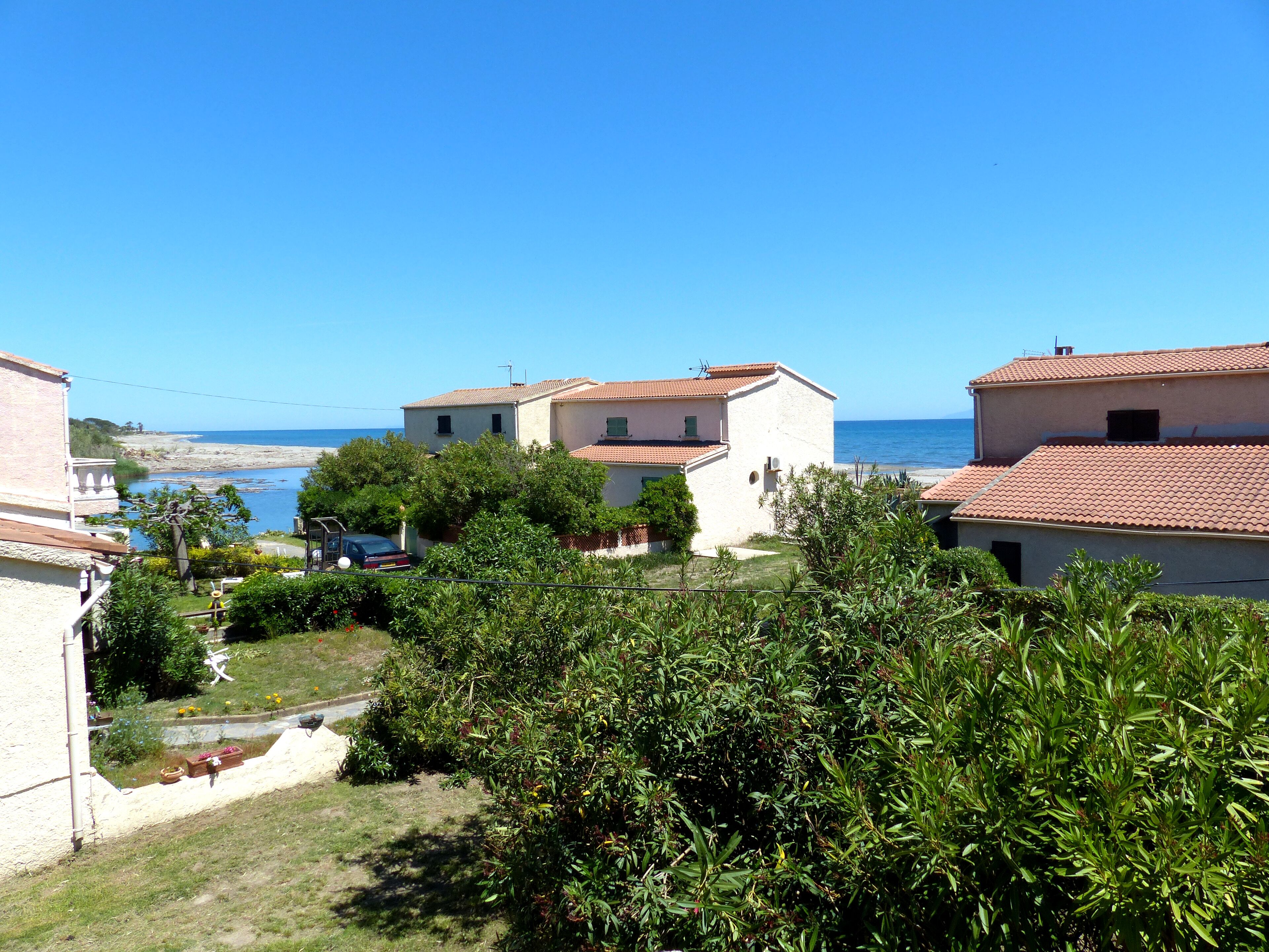 A coastal residential area with houses, a clear sky, and a view of the sea.