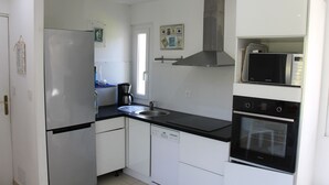 Una cocina moderna con electrodomésticos de acero inoxidable, armarios blancos y encimera negra.