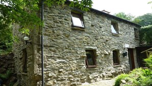 A stone building with multiple windows and a small garden area. - Detached, romantic, homely barn. Peaceful with lovely views. Garden. New kitchen (Kendal)