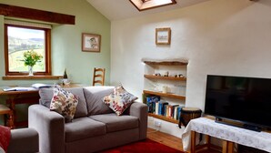 A cozy living room with a sofa, a television, and a bookshelf. - Detached, romantic, homely barn. Peaceful with lovely views. Garden. New kitchen (Kendal)