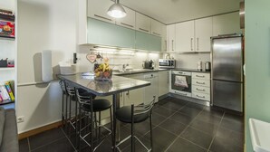 Eine moderne Küche mit einer zentralen Kochinsel, Barhocker, Edelstahlgeräten und einer Mikrowelle.