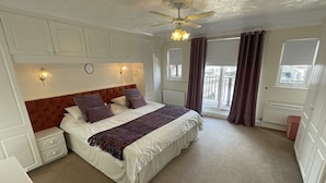 A bedroom with a bed, bedside tables, a ceiling fan, and a window with curtains.