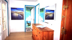 Un couloir avec une commode en bois, une porte et trois tableaux encadrés accrochés au mur.