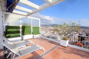 A balcony with white chairs, a potted plant, and a view of a cityscape. - ROOF VILLA above the roofs of Nice facing the sea 100 m² + 100 m² terraces (Nice)