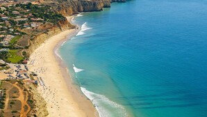 A coastal area with a sandy beach, a cliffside, and a small settlement with buildings. - Luxury villa with private infinity pool and magnificient sea views (Lagos)