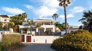 A modern multi-story building with a paved entrance, surrounded by palm trees and a well-maintained garden. - Luxury villa with private infinity pool and magnificient sea views (Lagos)