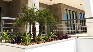 A modern two-story building with a balcony, large windows, and a landscaped area with plants. - Luxury villa with private infinity pool and magnificient sea views (Lagos)