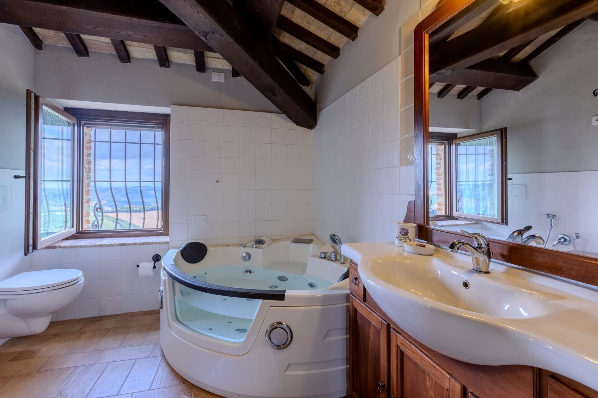 A bathroom with a bathtub, a sink, and a toilet. There are windows with views of the outside.