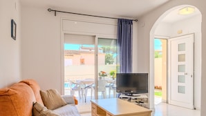 Una sala de estar moderna con sofá, televisor y escritorio.